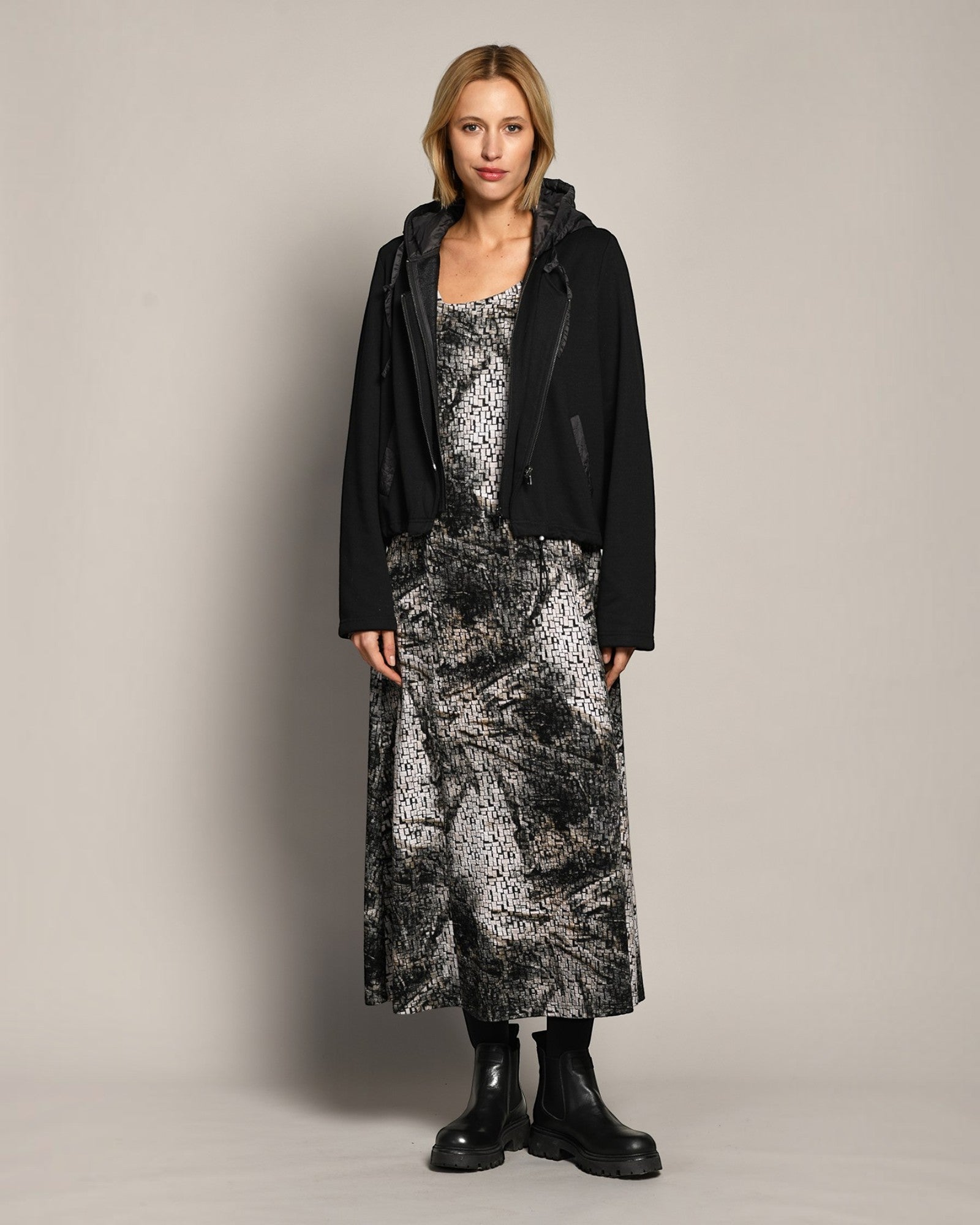 LEEZZA model wearing an AMBER & MOON DORA long jacquard jersey dress with a subtle print and a black hooded jacket.